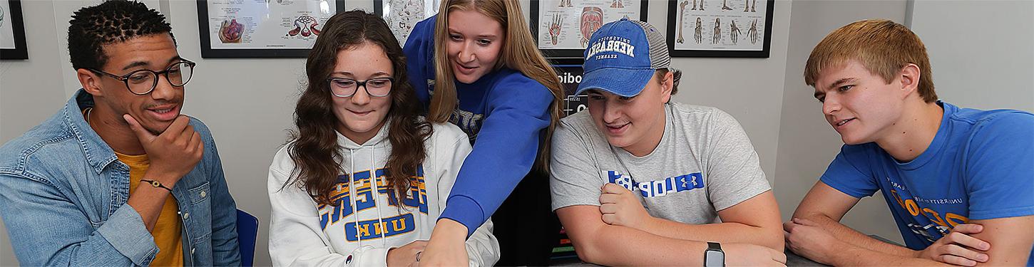 Students in a study group gather around a laptop